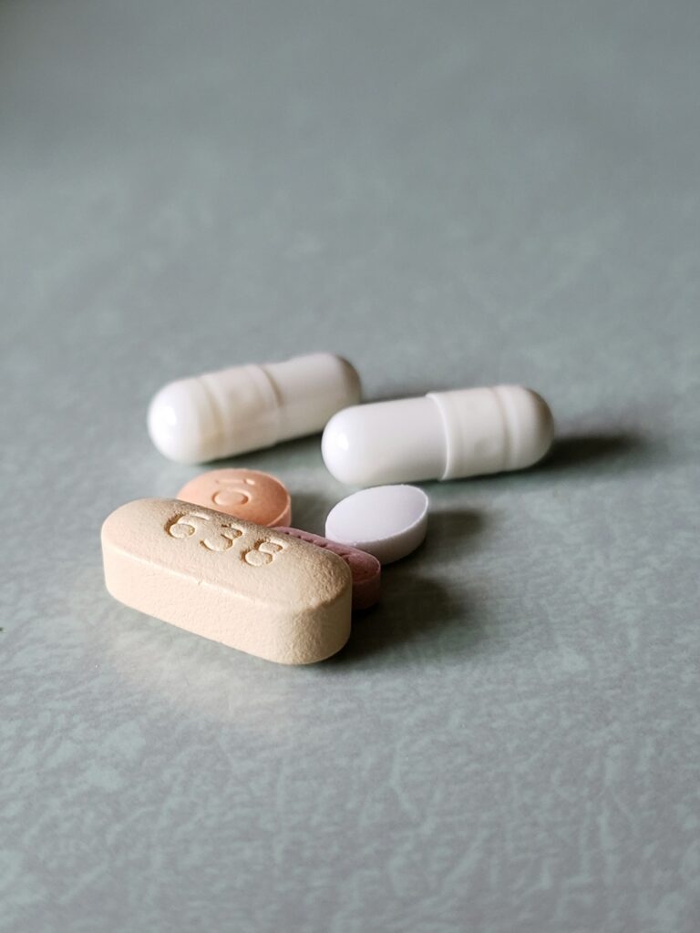 A collection of five pills of different shapes and sizes on a gray background.