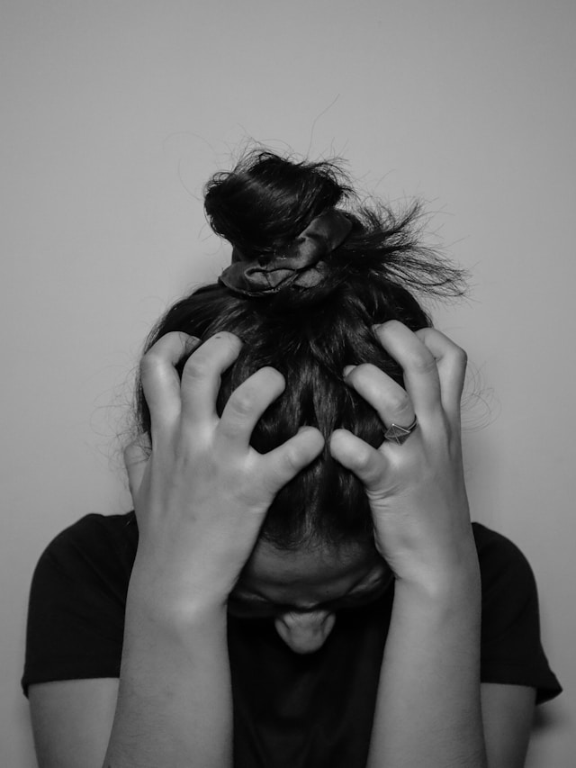 A woman covering her face with her hands, in black and white.